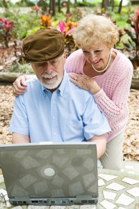 Happy senior couple using their laptop computer outdoors. Focus on husband.